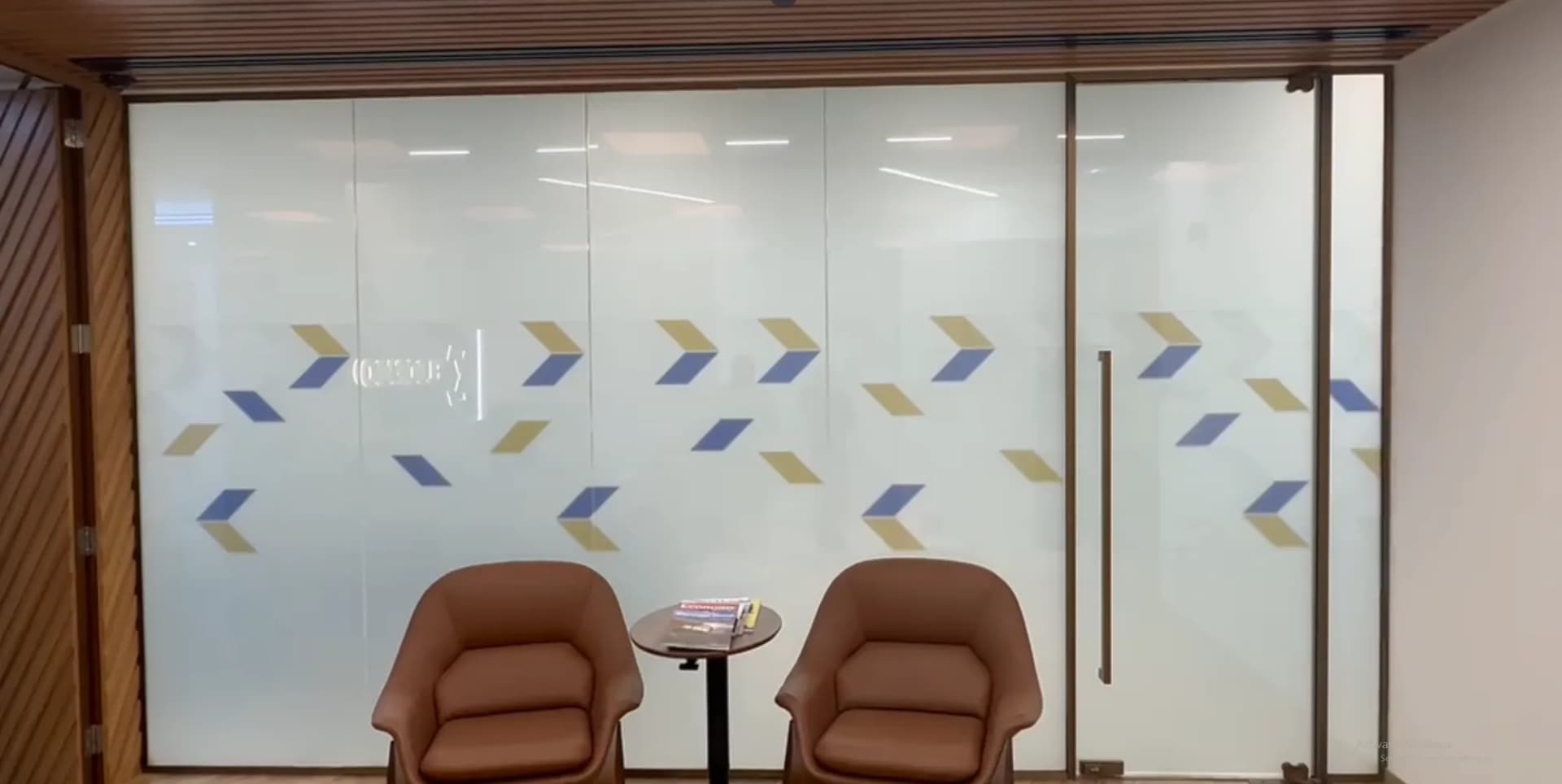 Office glass partition with a frosted film pattern and applied brand mark