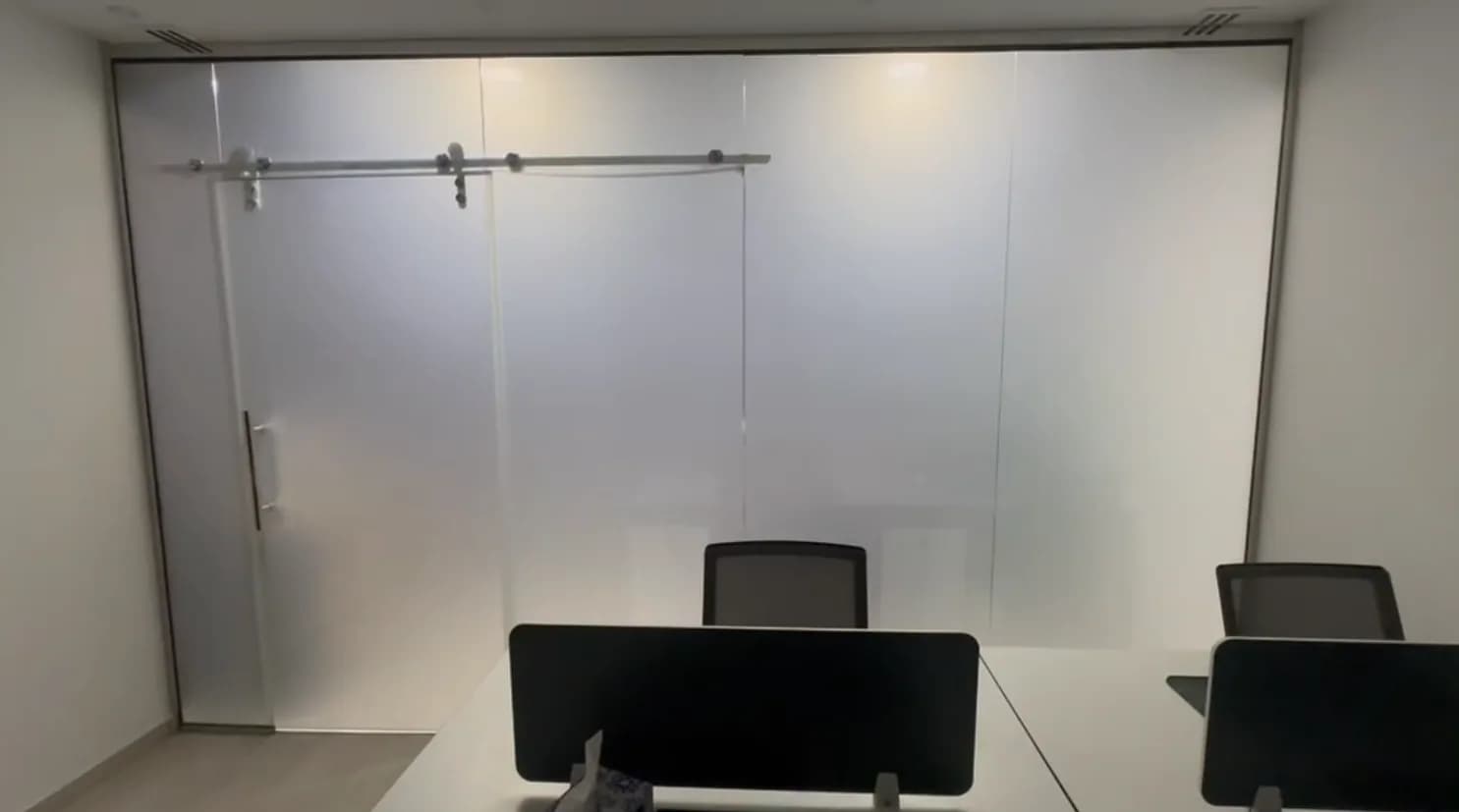 Meeting room enclosed by a full-height frosted privacy partition with a sliding door